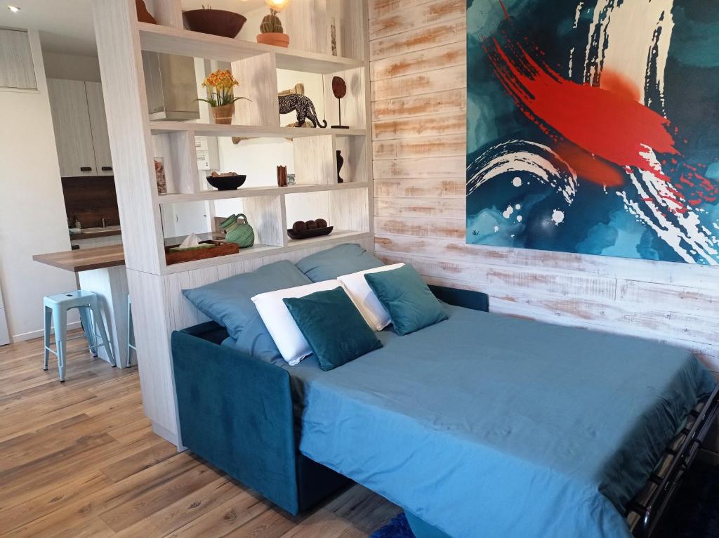 Un dormitorio con una cama azul con almohadas. en Le relais des bains en Paladru
