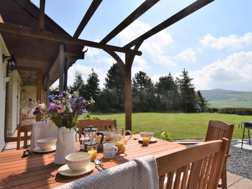 un tavolo in legno con fiori e bicchieri su un patio di 3 Bed in Brecon 83076 ad Aber-Brân
