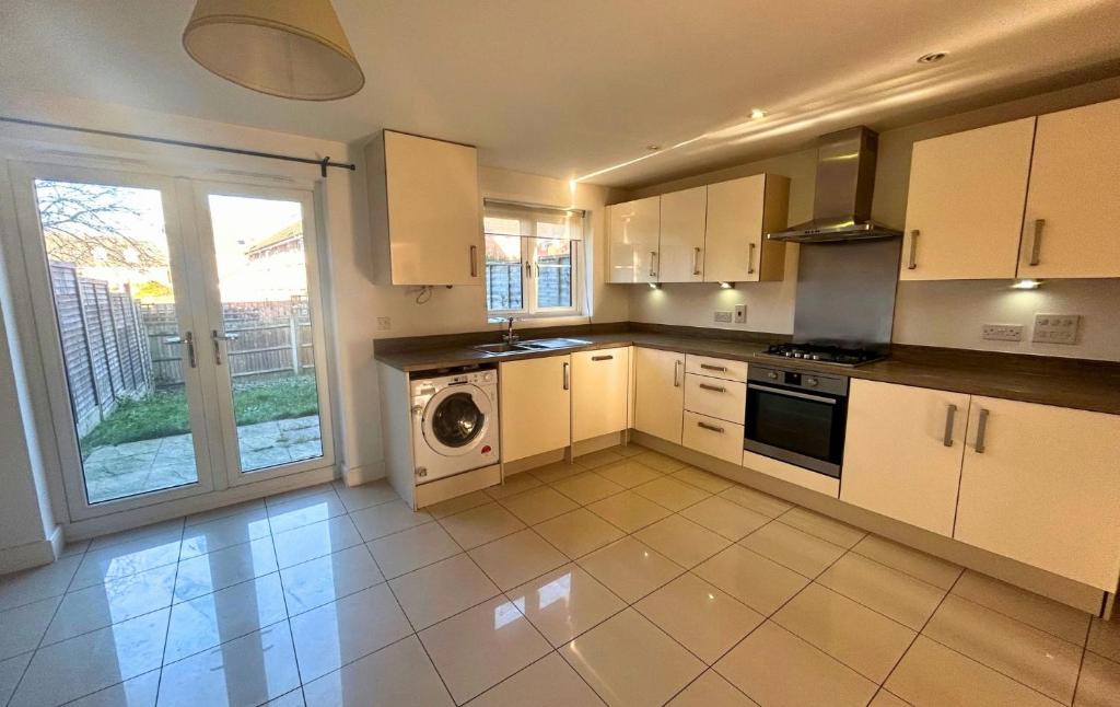 a kitchen with white cabinets and a washer and dryer at Taplow Stunning Four Bedroom Townhouse in Taplow