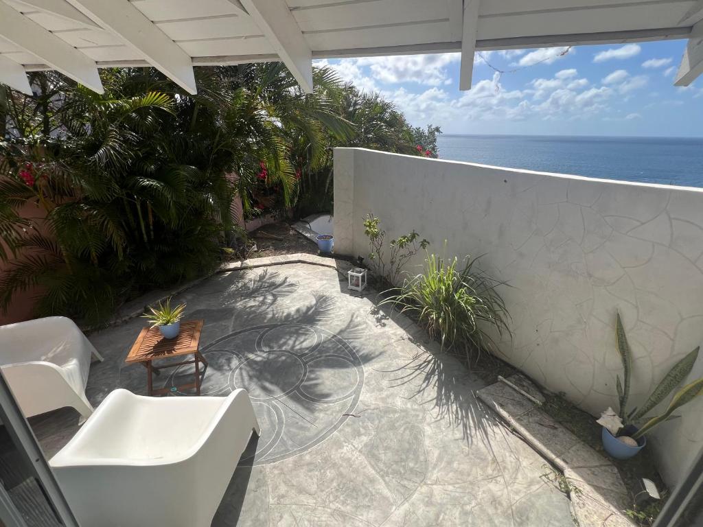 une terrasse avec une table et des chaises et l'océan dans l'établissement Cozzy Apartment on the Caribbean side-Frigate Bay, à Frigate Bay