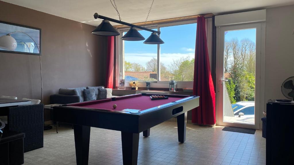 - un salon avec un billard devant une fenêtre dans l'établissement Le Panache, à Sevremont
