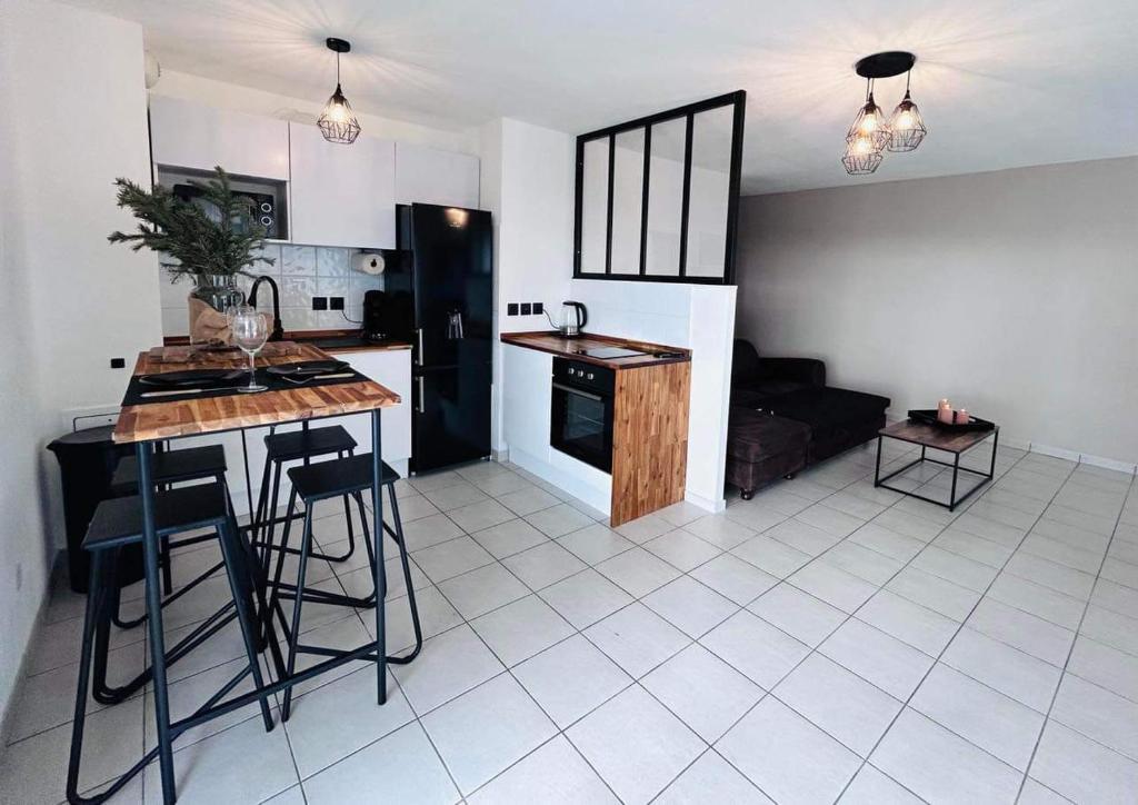 Il comprend une cuisine et un salon avec un réfrigérateur noir et une table. dans l'établissement Lormont City, proche Bordeaux, piscine et parking, à Lormont