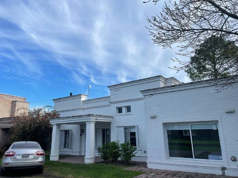 瓜萊瓜伊丘的住宿－Casa Country Golf Club, Pagos en USD，前面有一辆汽车停放的白色房子