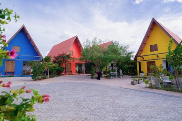 um grupo de edifícios coloridos em uma estrada de tijolos em Vila Feliz - Chalés completos - ideal para famílias em Serra de São Bento