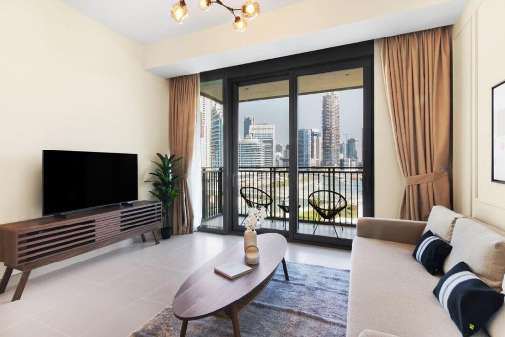 een woonkamer met een televisie en een groot raam bij Silkhaus elegant 1BDR pad with Marina and Beach views new building in Dubai