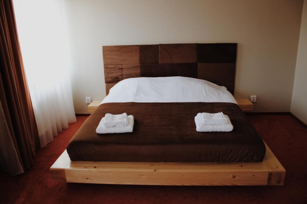 a bedroom with a bed with two white shoes on it at Popasul Graniceresc in Năsăud