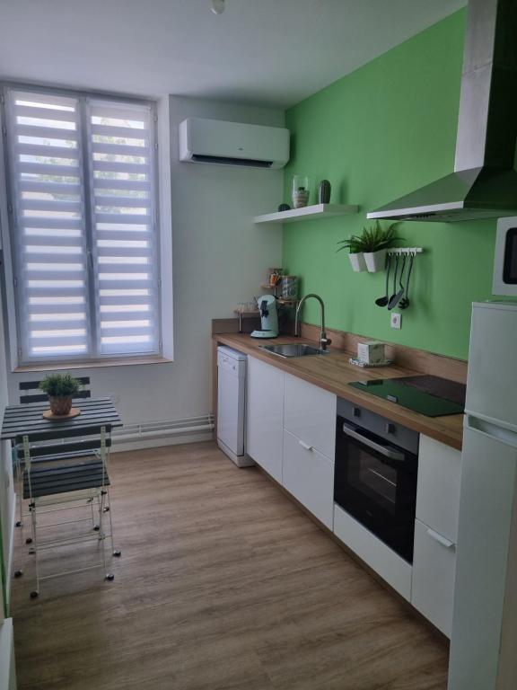 uma cozinha com paredes verdes, um lavatório e uma mesa em La Cigale em Soissons