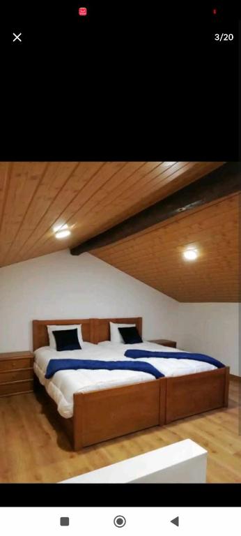 sypialnia z dużym łóżkiem i drewnianym sufitem w obiekcie Moradias dos Castelos (Azul ) w mieście Ourém