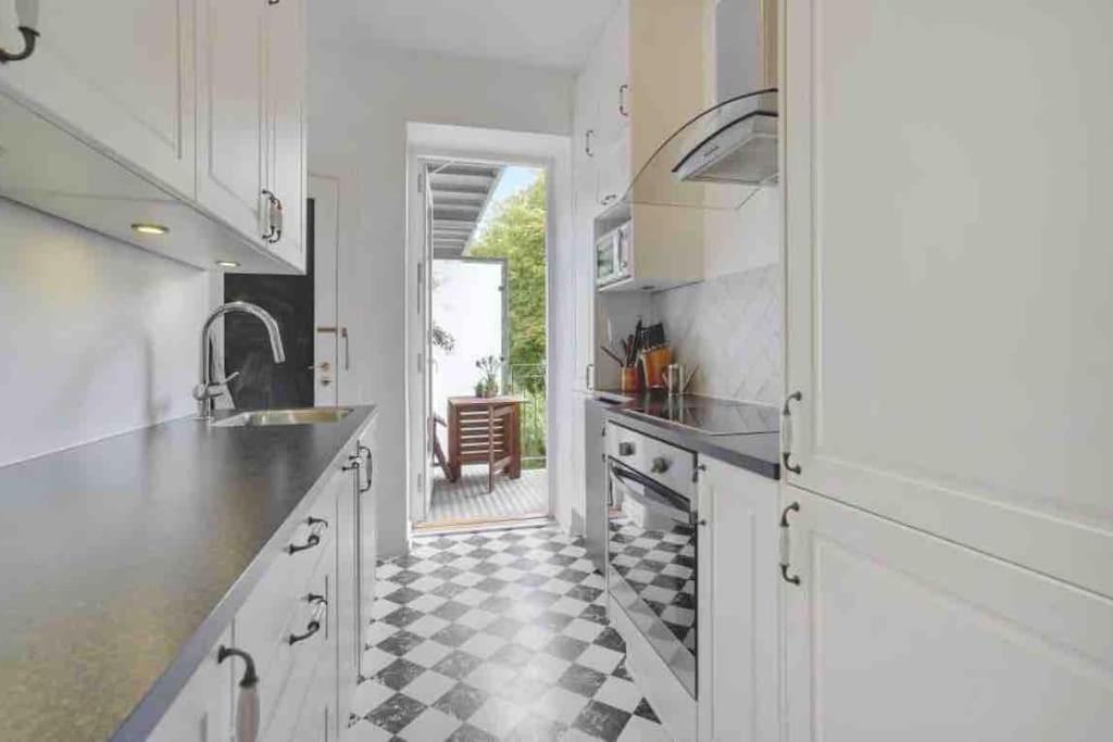 a kitchen with white cabinets and a checkered floor at Cozy appartment for 2 in Aarhus in Aarhus