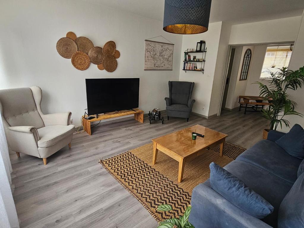 a living room with a tv and a couch and a table at Le Regent City of Design in Saint-Étienne