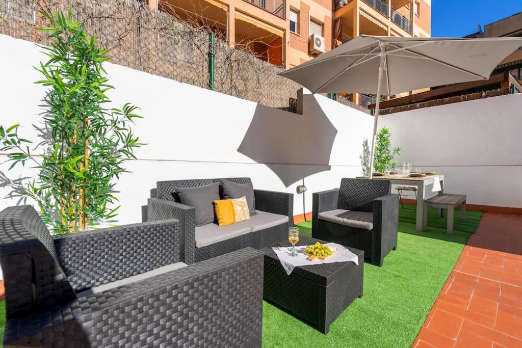 a patio with chairs and an umbrella and grass at Enamorats in Barcelona