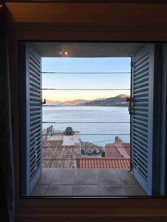 una ventana con vistas al agua desde una casa en Appartement de 2 chambres a L'Ile Rousse a 50 m de la plage avec terrasse et wifi, en LʼÎle-Rousse