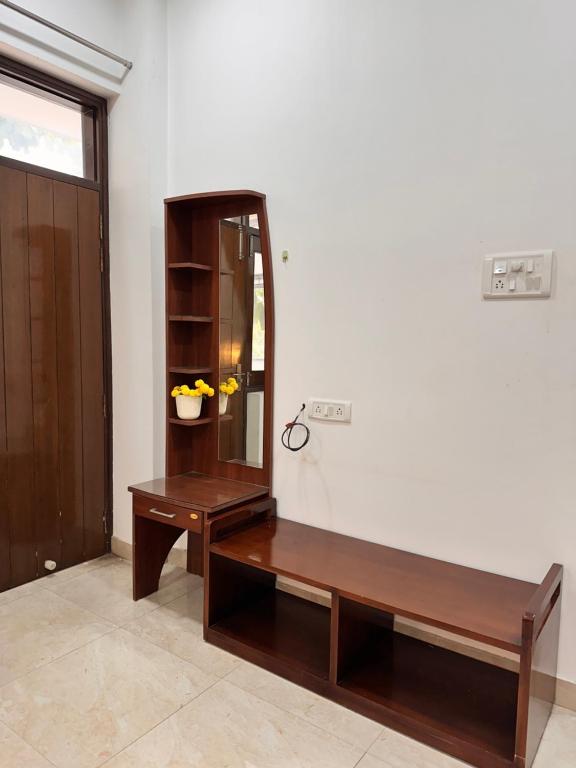 a room with a wooden bench and a mirror at Teak Stays in Prayagraj