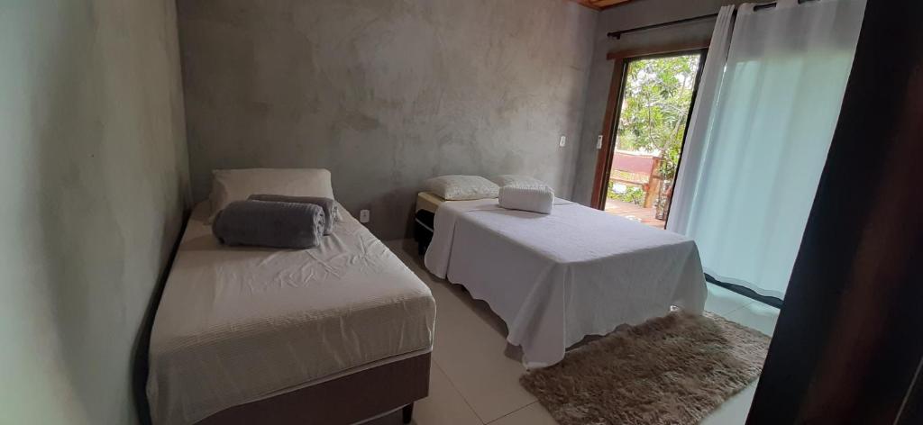 a small room with two beds and a window at Casa das Orquídeas in Bonito