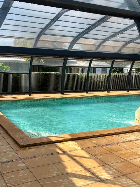 a swimming pool with a roof and blue water at Mobilhome camping les petits écureuils 4 étoiles Biscarrosse in Biscarrosse