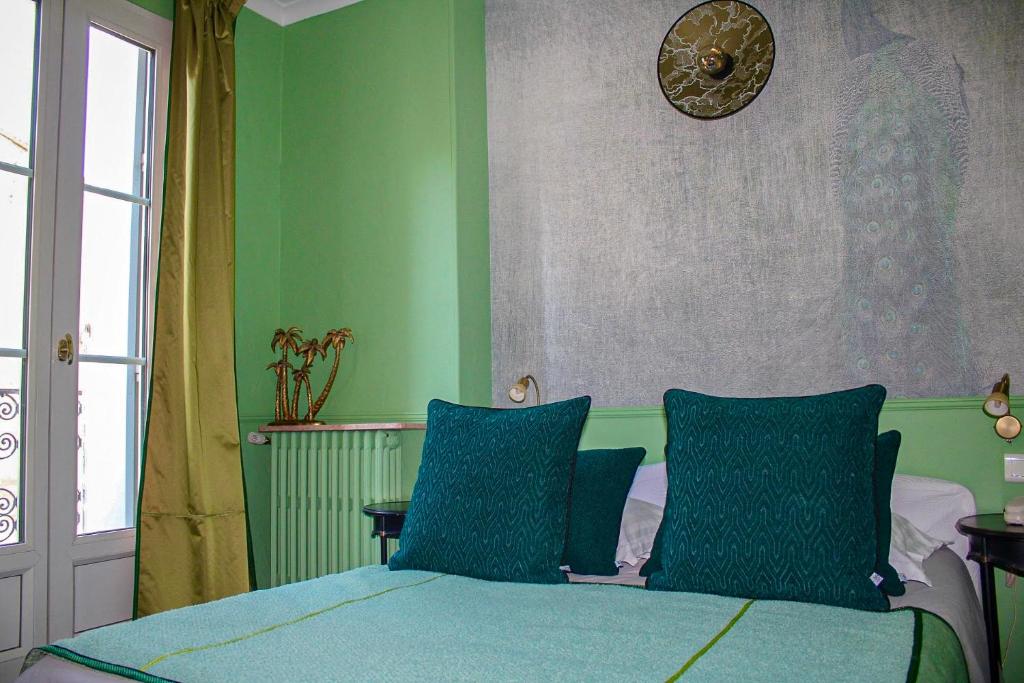 ein Schlafzimmer mit grünen Wänden und einem Bett mit blauen Kissen in der Unterkunft Hotel du Palais in Montpellier