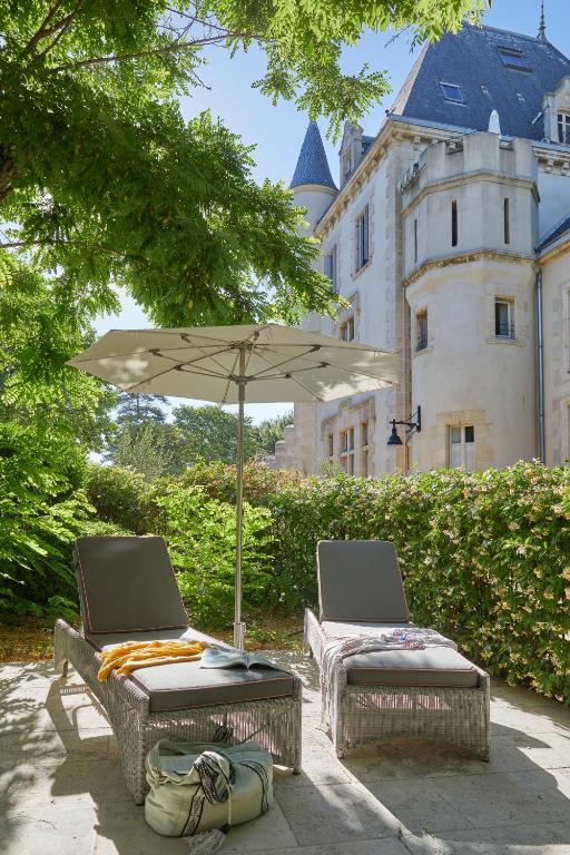 two chairs and an umbrella in front of a castle at Château Les Carrasses in Capestang