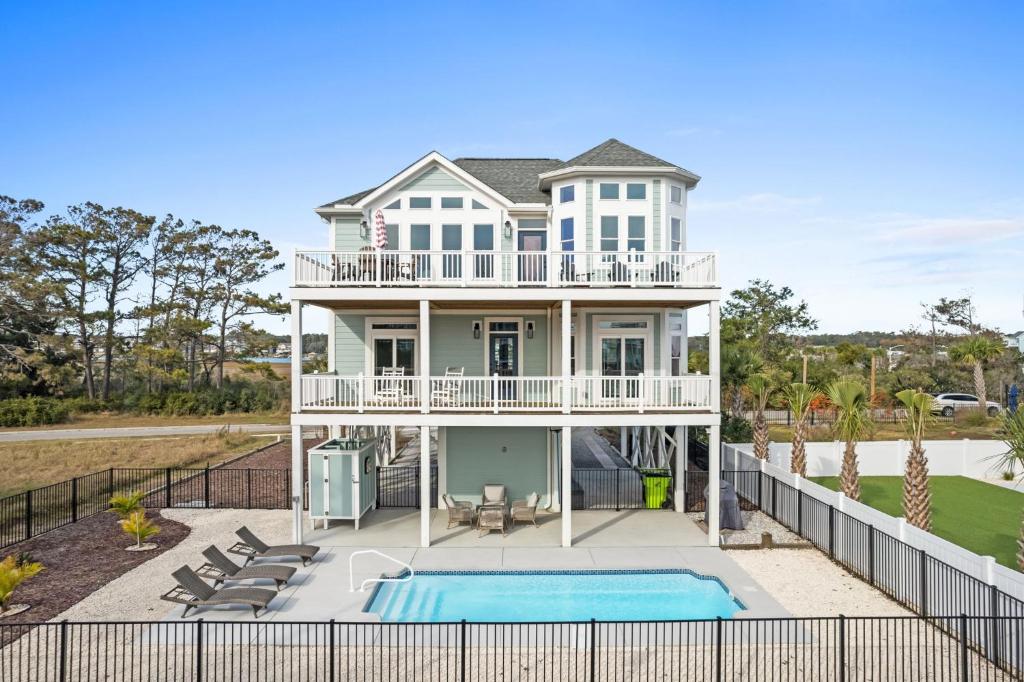 a house with a swimming pool in front of it at Coastal Charm Ocean Isle Beach custom beach home with 4 bedroom, 3 bath home with pool and elevator in Ocean Isle Beach