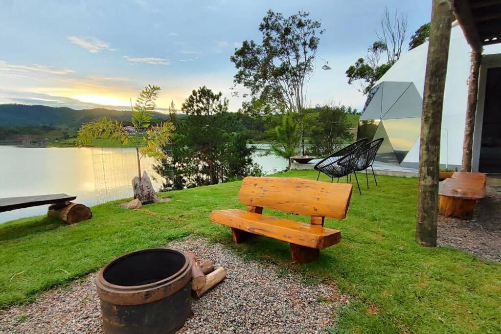 um banco sentado ao lado de um barril e uma fogueira em Lunar HOME (Casa Bolha) Pé na água em Joanópolis