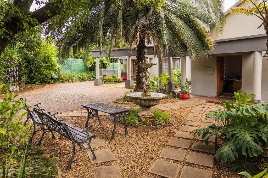 a courtyard with a fountain and a table and benches at Rozendal Guest House in Centurion