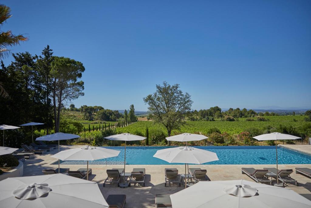 a pool with tables and chairs and umbrellas at Château Les Carrasses in Capestang