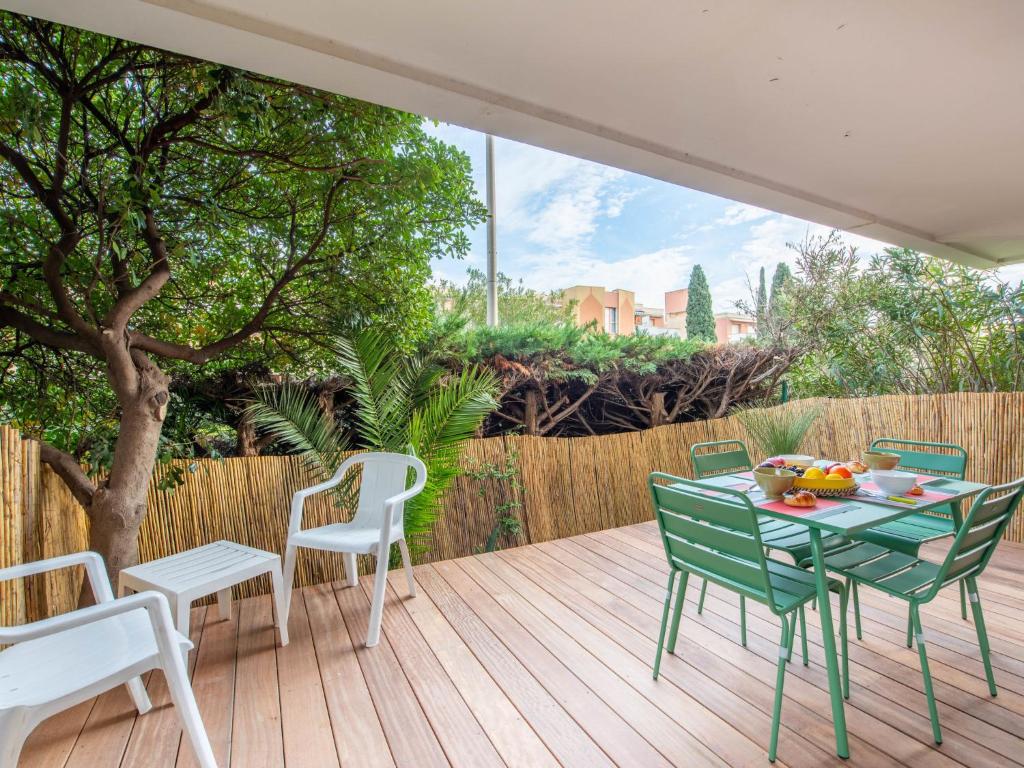 une terrasse en bois avec une table et des chaises. dans l'établissement Apartment La Croix du Sud-23 by Interhome, à Cavalaire-sur-Mer