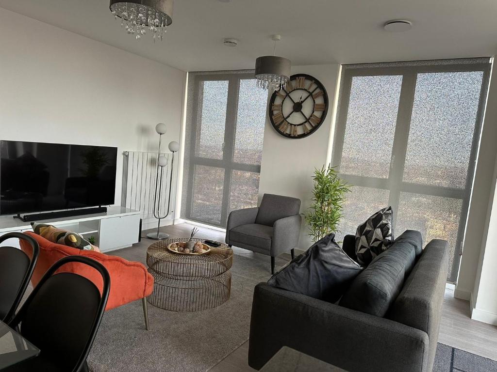 a living room with a couch and a clock on the wall at Immaculate 2-Bed Apartment in east London in London