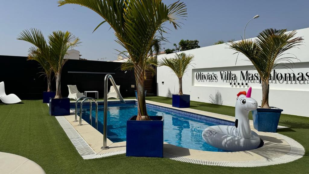 a pool with palm trees and an inflatable shark next to it at Villa Olivia Maspalomas with private pool in Maspalomas