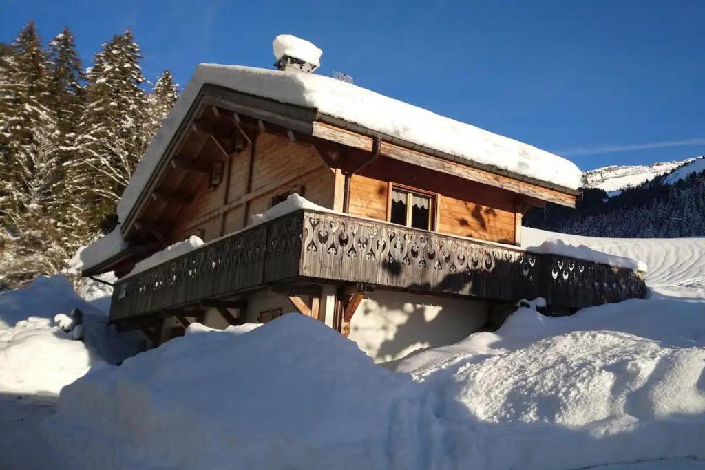 Cabaña de madera cubierta de nieve con balcón en 9-Bed Chalet with Easy Access to Avoriaz 1800, en Morzine
