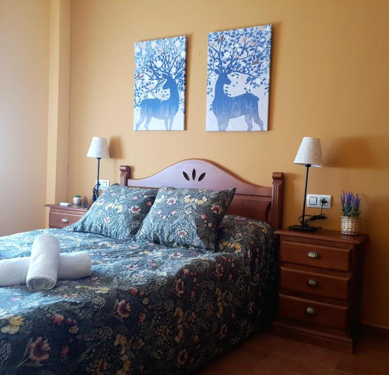 a bedroom with a bed and three paintings on the wall at Mirador de la cueva in Enguídanos