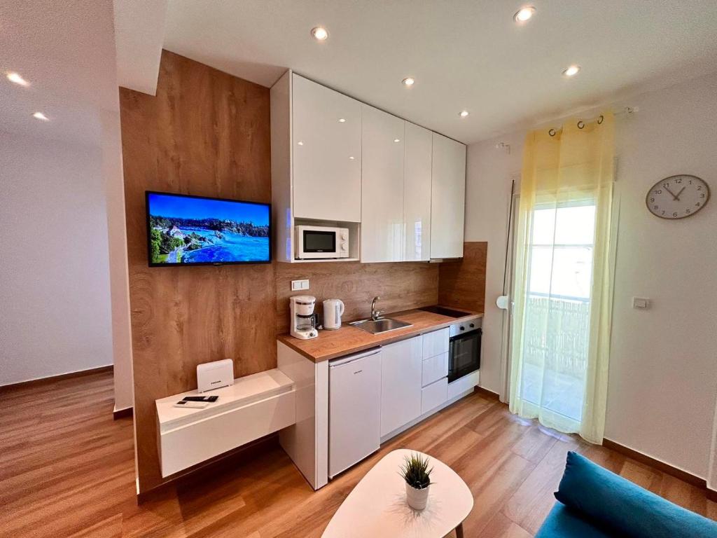 a kitchen with white cabinets and a tv on the wall at Relax Apartment II in Perea