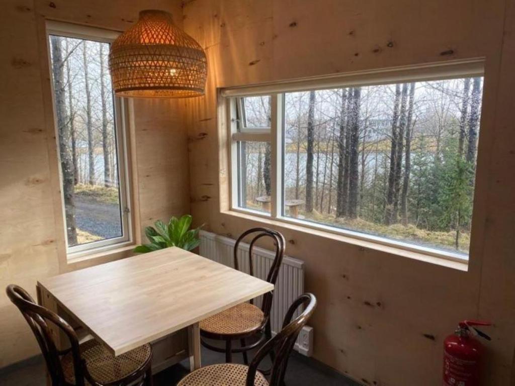 a wooden table and chairs in a room with windows at Audkula Dome Cabin in Hella