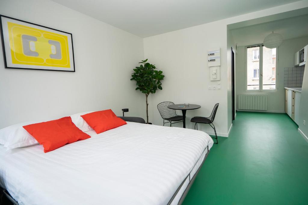 - une chambre avec un lit blanc, une table et des chaises dans l'établissement Alma, au Havre