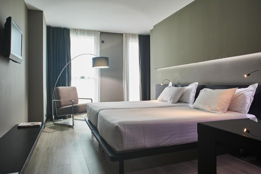 Una habitación de hotel con una cama grande y una silla. en Silken Gran Teatro, en Burgos