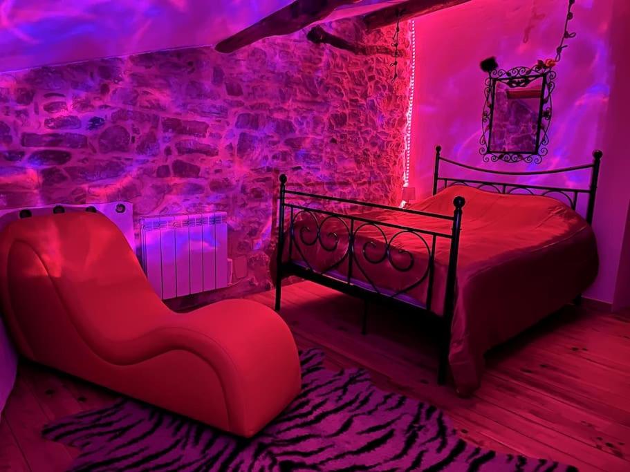 - une chambre avec un lit, une chaise et des lumières violettes dans l'établissement Love room de Blanche Neige, à Assignan