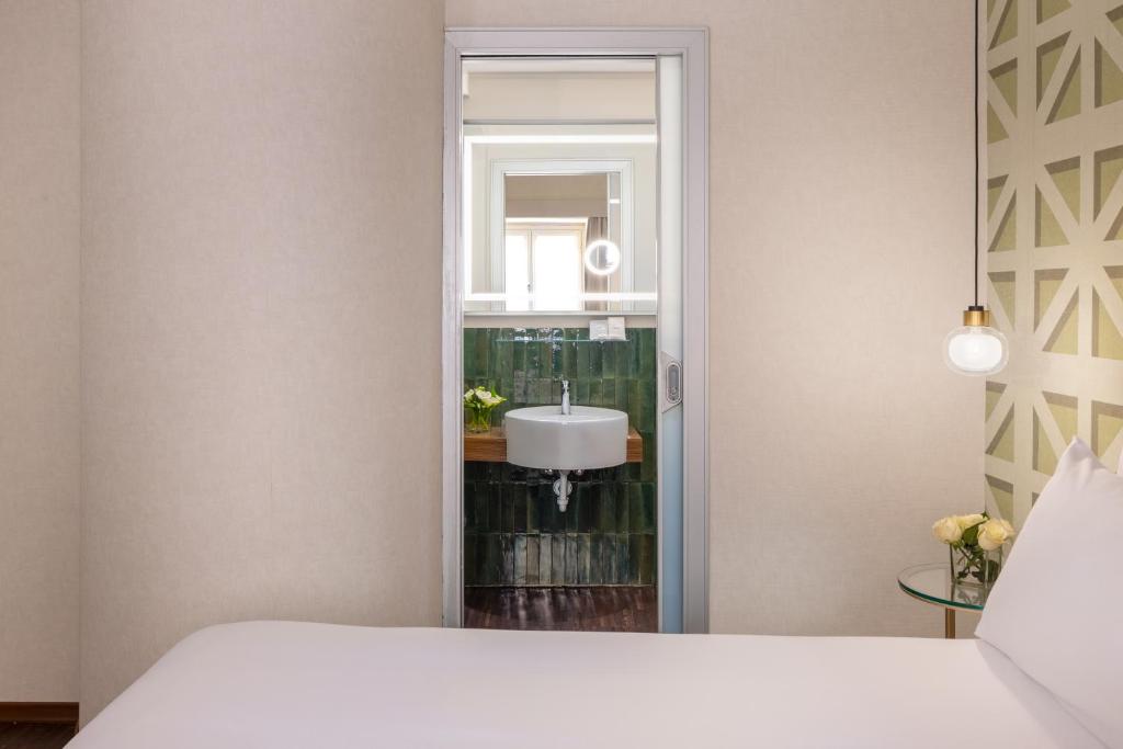 a bedroom with a bed and a sink and a mirror at Maison Roma Piazza di Spagna UNA Esperienze in Rome