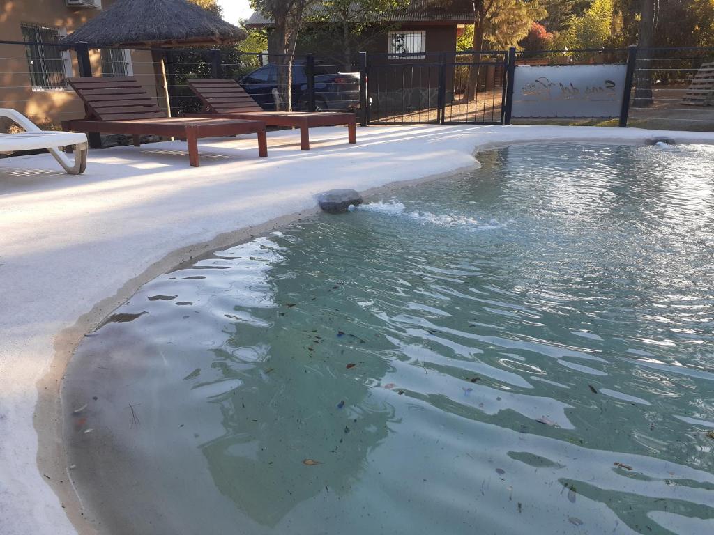 una piscina de agua con un banco al lado en Cabañas Ecos del Valle en Los Reartes