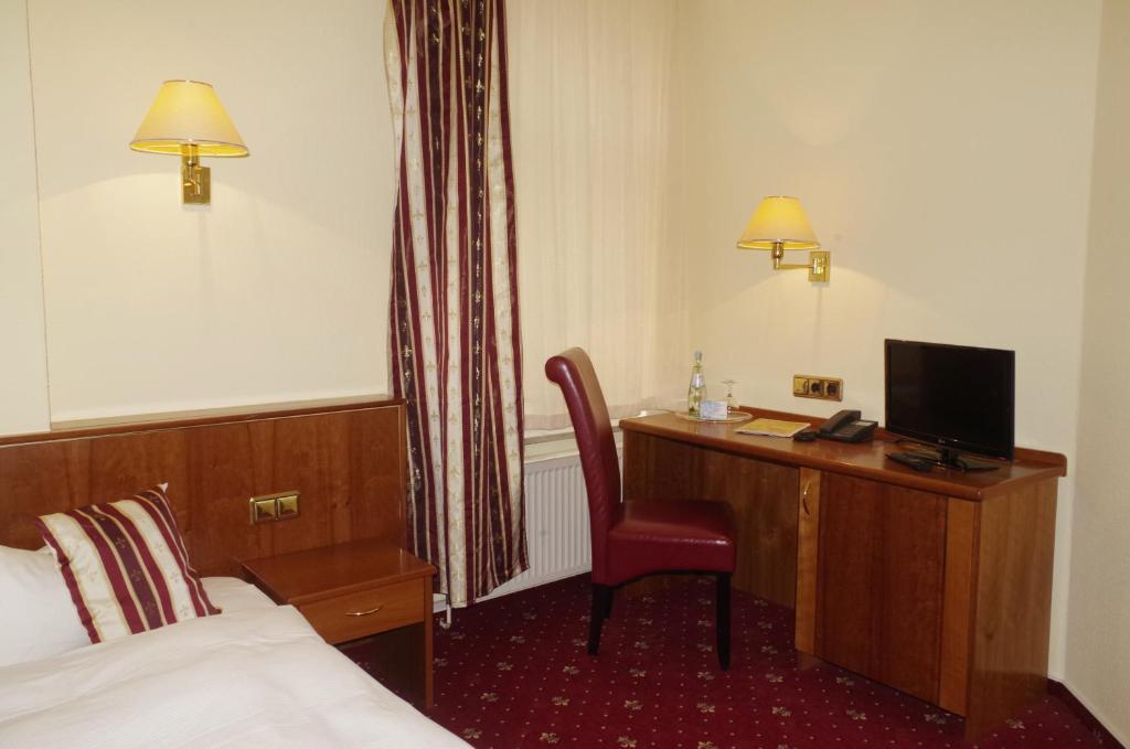 a hotel room with a bed, desk and television at Hotel Merseburger Hof in Leipzig