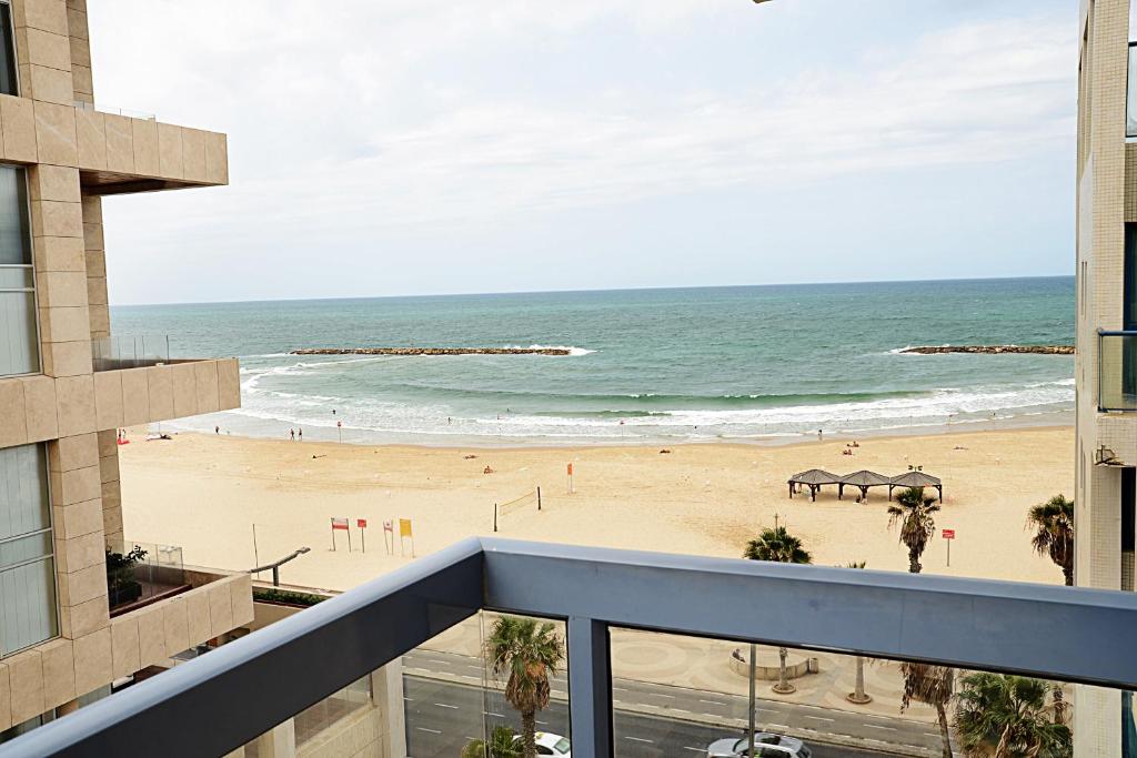 Blick auf den Strand vom Balkon eines Gebäudes in der Unterkunft Abratel Suites Hotel in Tel Aviv