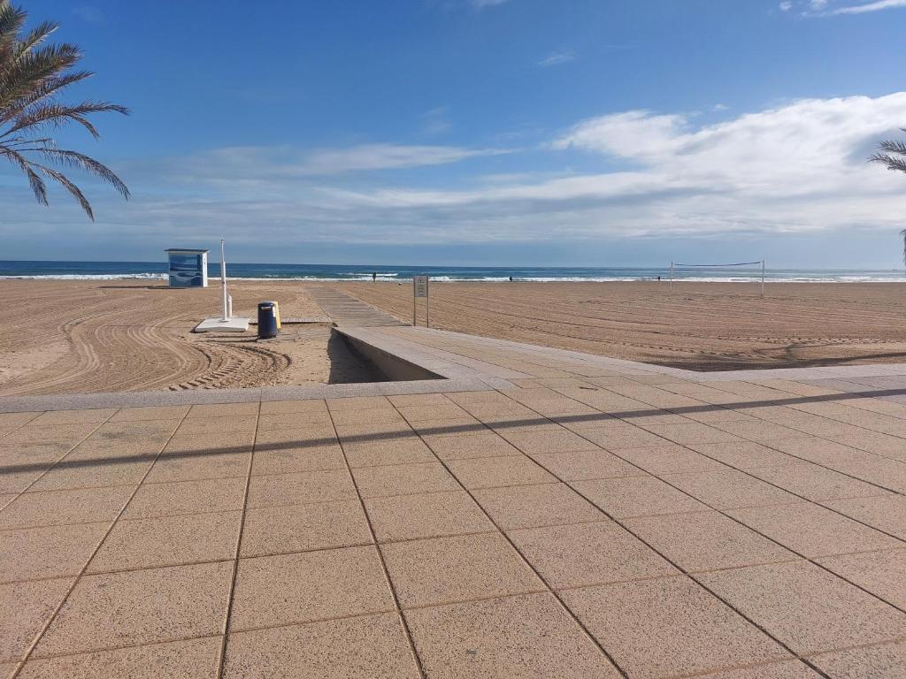 Precioso apartamento en Gandía في Playa de Gandia: شاطئ رملي مع سلة مهملات جانبية