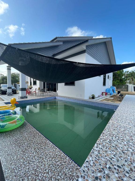 a house with a swimming pool in front of a house at Homestay PCB Villa MamaKaya in Kota Bharu