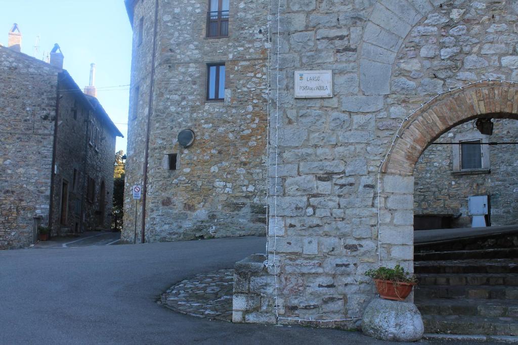 un edificio in pietra con un arco accanto a una strada di La Torre di Melezzole a Melezzole