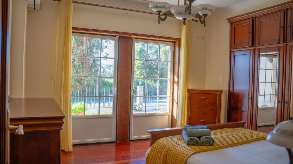a bedroom with a bed and two large windows at SERENIDADE ROOMS in Terrugem
