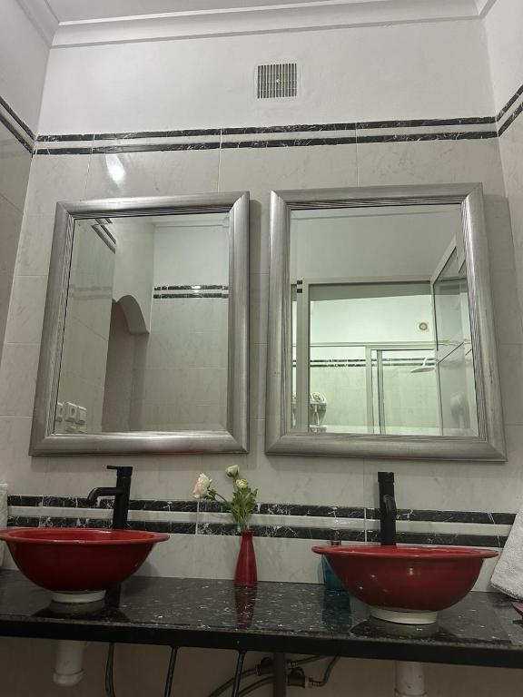 two red sinks in a bathroom with two mirrors at Riad Ras Lafaa in Safi
