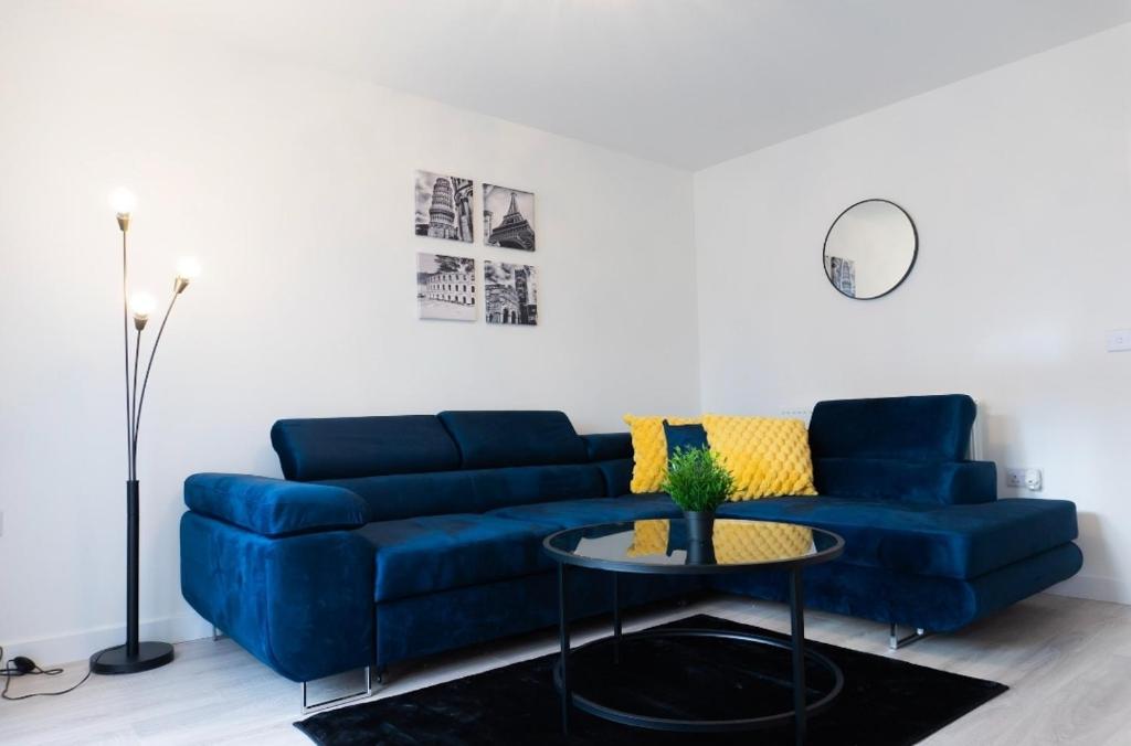 a living room with a blue couch and a table at Stylish House with Private parking in Glasgow