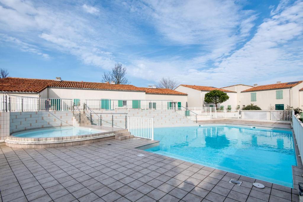 una piscina en medio de un patio con una casa en Appartement Océanis avec Piscine proche du port, en Saint-Martin-de-Ré