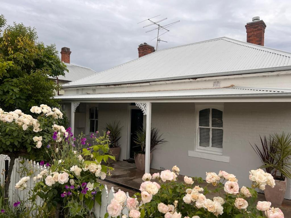 a white house with flowers in front of it at 1880 Cottage in Tumut