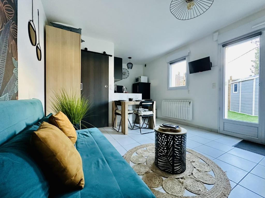 un salon avec un canapé bleu et une table dans l'établissement Charmant studio rénové, quartier Saint Michel, proche centre-ville - Les Sables, à Les Sables-dʼOlonne