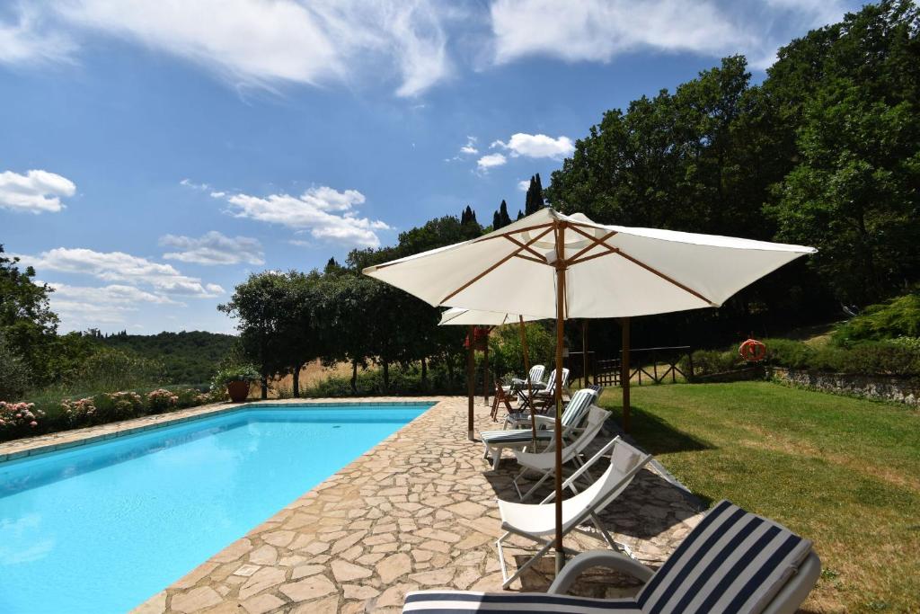 eine Gruppe Stühle und ein Sonnenschirm neben einem Pool in der Unterkunft Podere Le Muricce in Siena