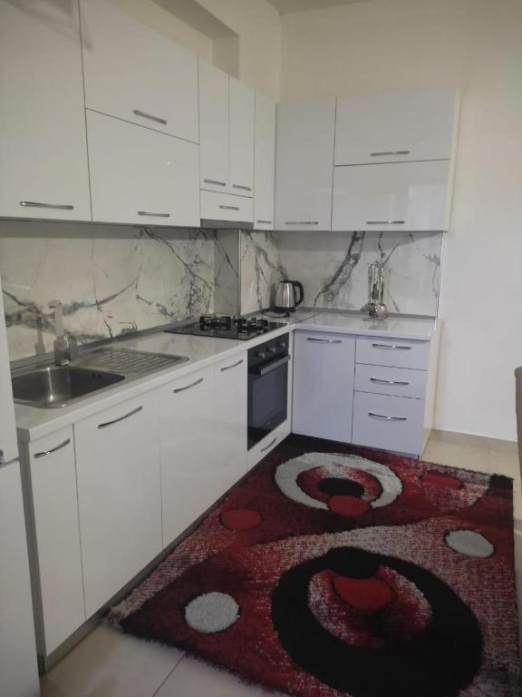 a kitchen with white cabinets and a rug on the floor at CITY CENTER 2 in Shkodër